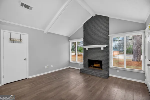a view of an empty room with wooden floor fireplace and a window
