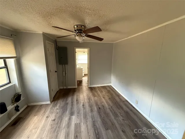 a view of empty room with wooden floor and fan