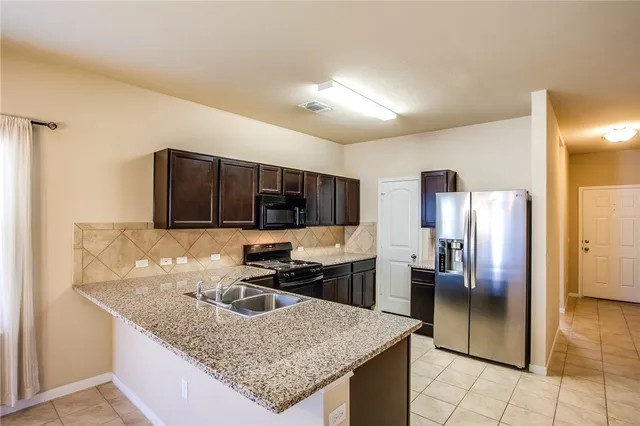 a kitchen with stainless steel appliances granite countertop a stove a sink and a microwave