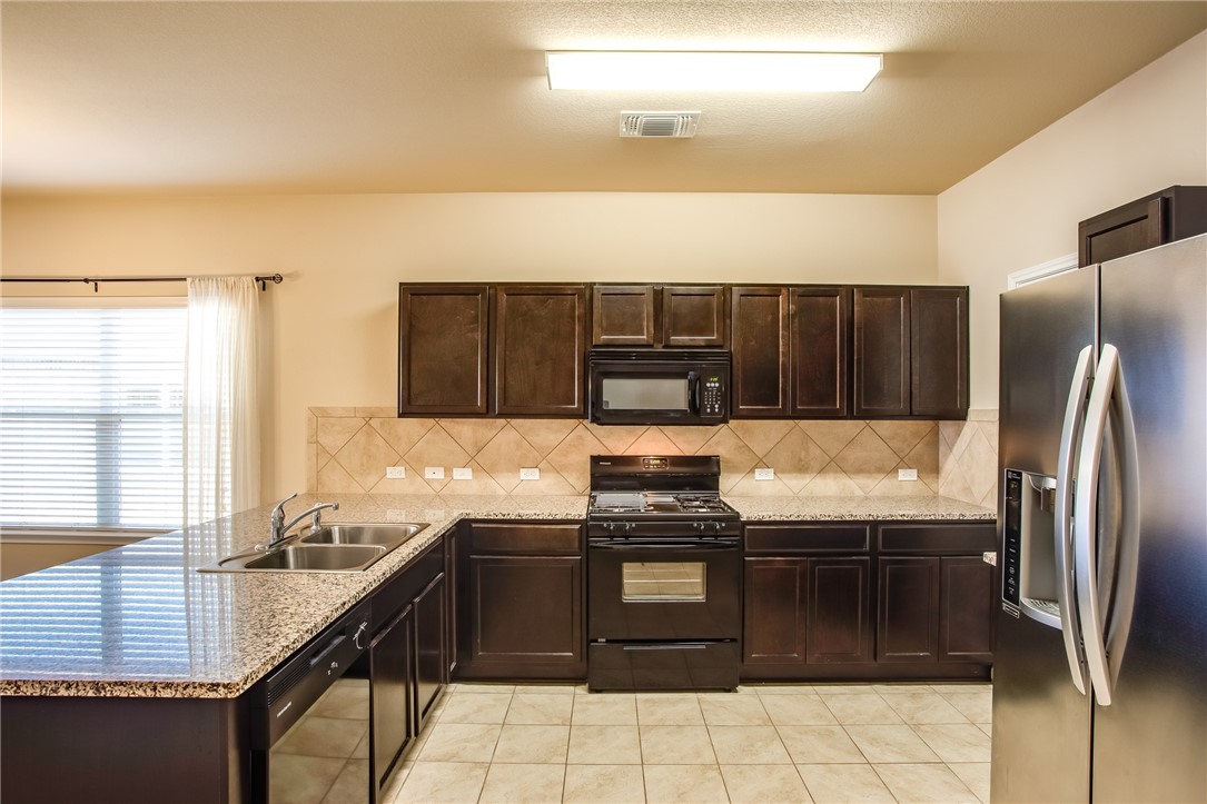 607 Brashear Lane Cedar Park, TX 78613 - Photo 12 of 28 a kitchen with stainless steel appliances granite countertop a stove a sink and a microwave