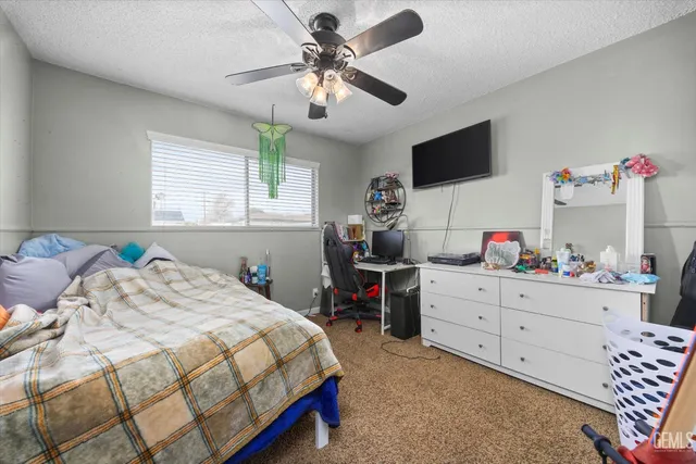 a bedroom with a bed and a flat tv screen on dresser