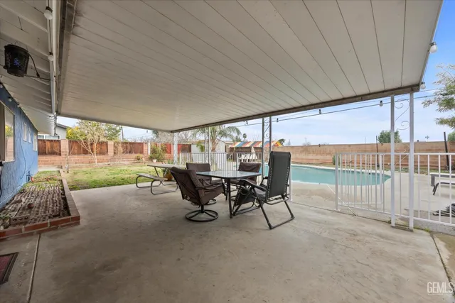 a view of a patio with table and chairs floor to ceiling window with yard and garden