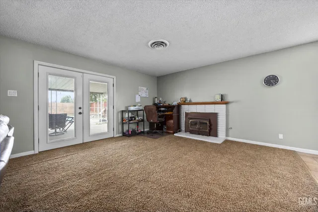 a view of an empty room with fireplace and windows