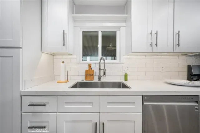 a kitchen with stainless steel appliances granite countertop white cabinets a sink a stove a microwave and a refrigerator