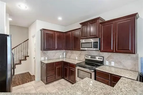 a kitchen with stainless steel appliances granite countertop wooden cabinets a stove top oven a granite counter top and a refrigerator