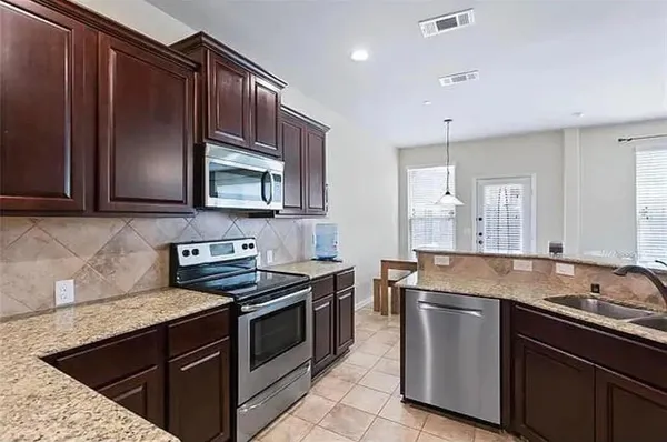 a kitchen with stainless steel appliances granite countertop a sink stove and microwave