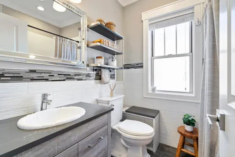 a bathroom with a granite countertop toilet sink and mirror