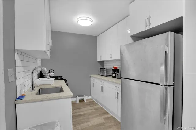 a kitchen with a refrigerator sink and white cabinets