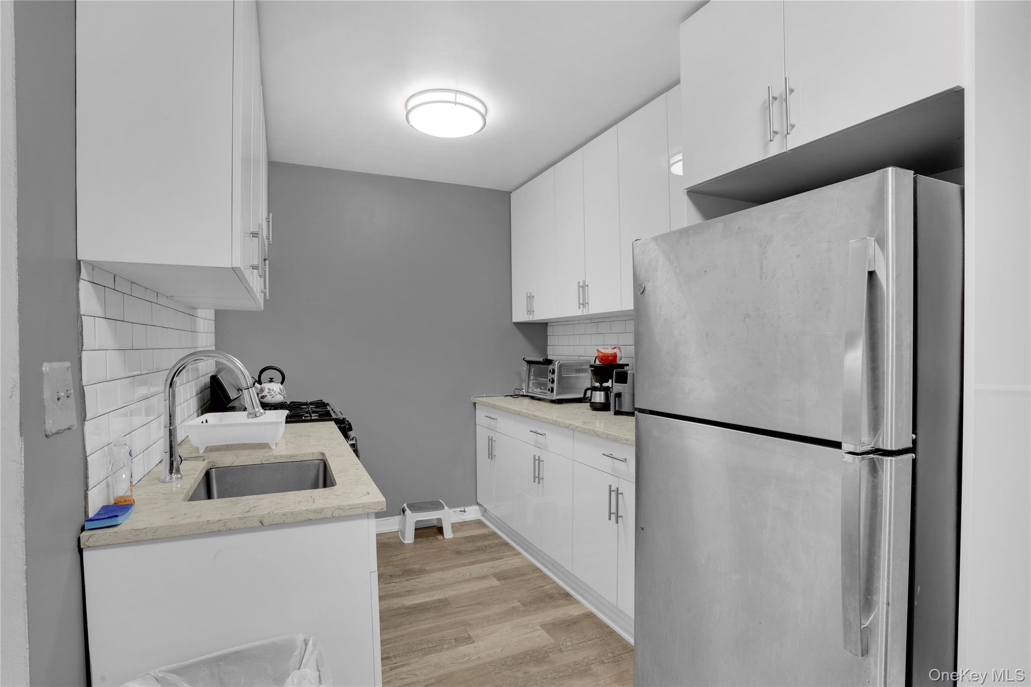 245 Bronx River Road, Unit 7C Yonkers, NY 10704 - Photo 8 of 23 a kitchen with a refrigerator sink and white cabinets