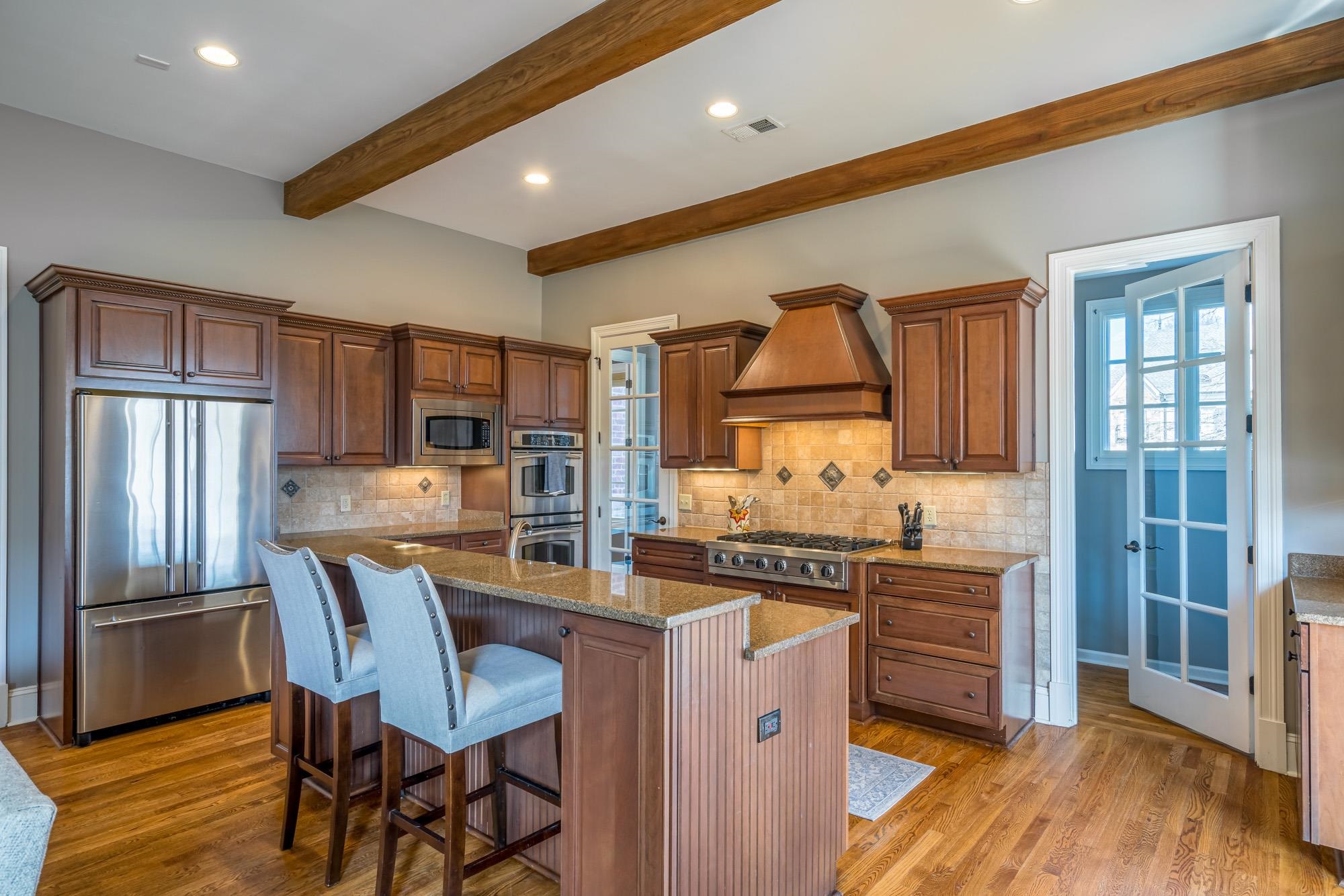 1247 Braywind Drive Collierville, TN 38017 - Photo 7 of 25 a kitchen with stainless steel appliances granite countertop a stove top oven a sink dishwasher a dining table and chairs with wooden floor