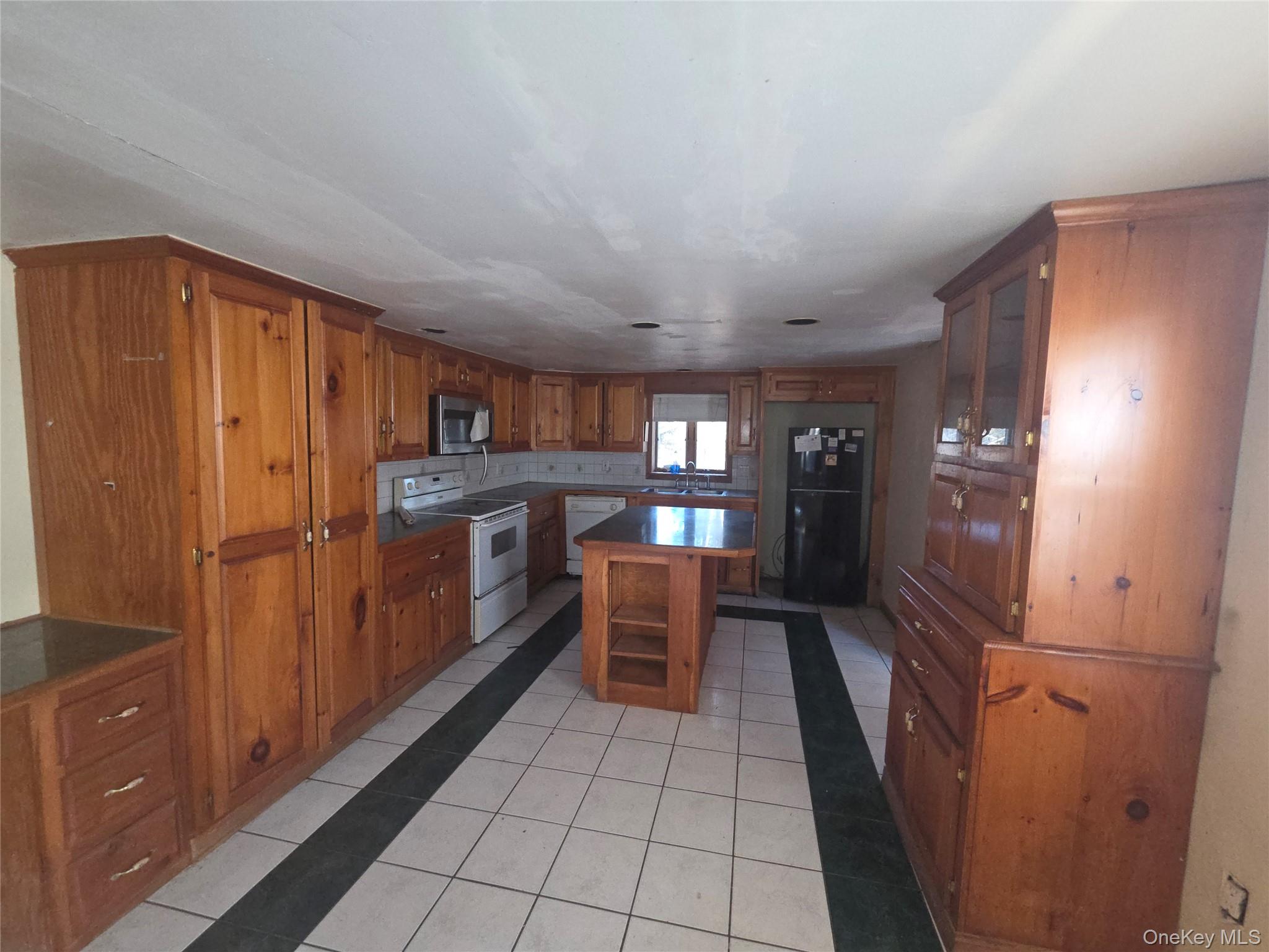 30 Matthews Drive Remsenburg, NY 11960 - Photo 4 of 11 a kitchen with a refrigerator and table chairs