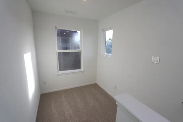 a view of an empty room with closet and mirror