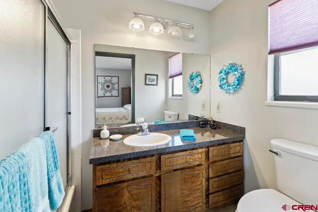 a bathroom with a granite countertop sink a toilet and a mirror