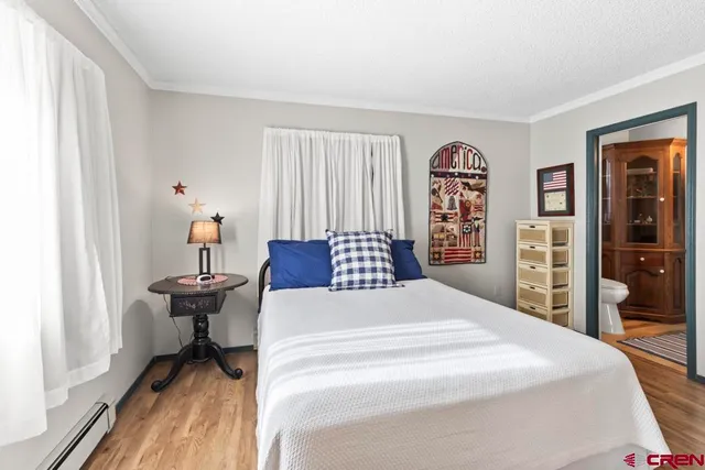 a spacious bedroom with a bed and a large mirror on the dresser