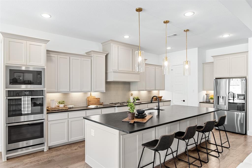 2808 Citation Road Celina, TX 75009 - Photo 10 of 40 a kitchen with stainless steel appliances a sink a stove a microwave a center island and cabinets