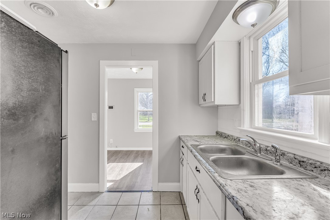 2521 Greenvale Road Cleveland, OH 44121 - Photo 10 of 23 Kitchen featuring a double basin stainless steel sink, white cabinetry with dark hardware, a stone-finish countertop, and tile flooring
