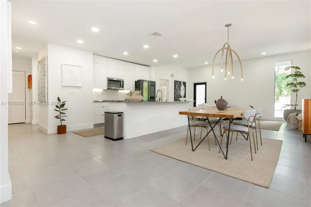 a kitchen with stainless steel appliances granite countertop a sink a stove a dining table and chairs