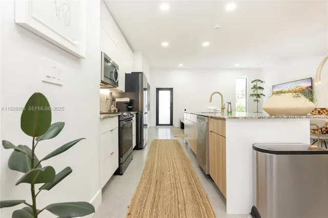 a kitchen with kitchen island granite countertop a sink and refrigerator