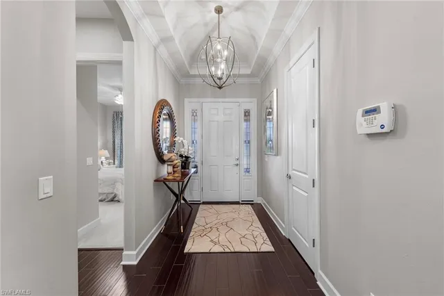 a view of a hallway with wooden floor and a chandelier