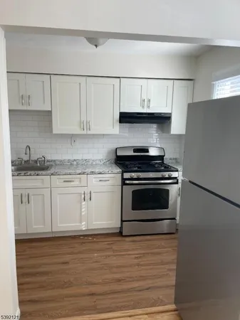 a kitchen with granite countertop white cabinets and stainless steel appliances