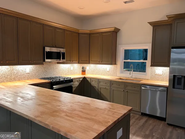 a kitchen with granite countertop wooden cabinets a stove top oven a sink and dishwasher