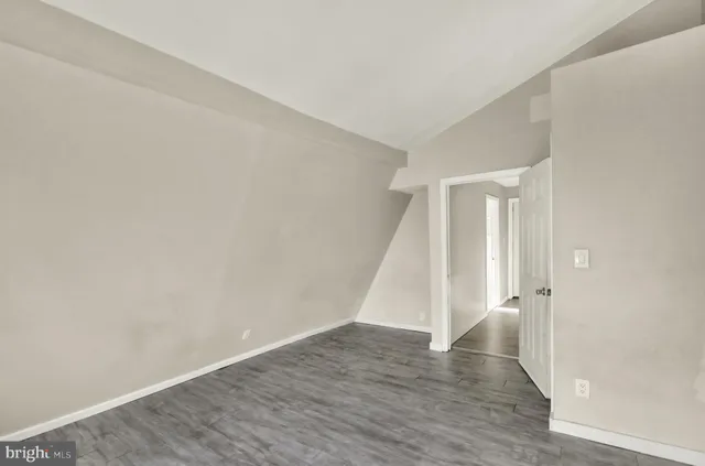 an empty room with wooden floor and staircase