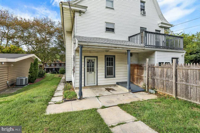 a view of a white house with a small yard and a large tree
