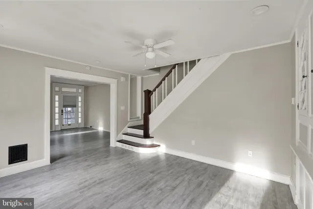 a view of empty room with wooden floor and fan
