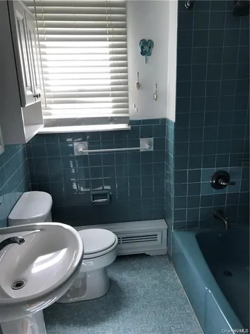 a white toilet sitting next to a bathroom sink and tub
