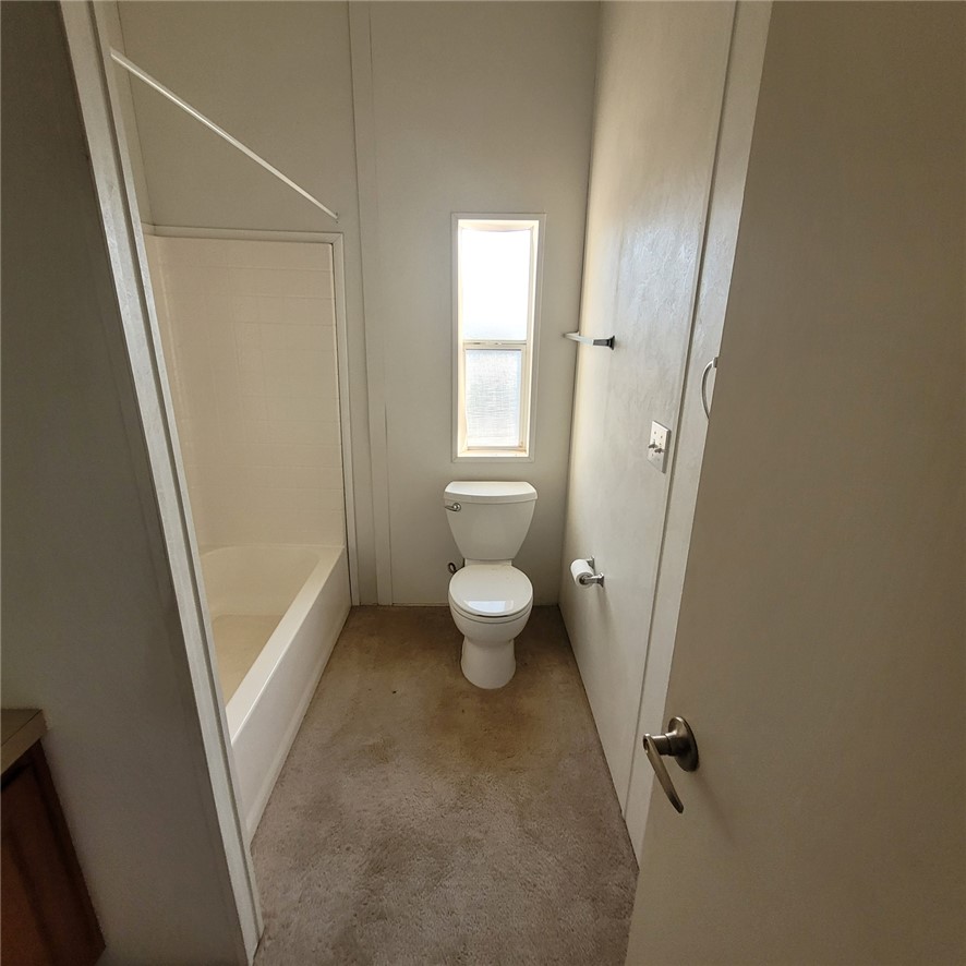 9732 2nd Street Chloride, AZ 86431 - Photo 26 of 28 Bathroom featuring a white toilet, a window providing natural light, a towel rack, and a bathtub with a shower
