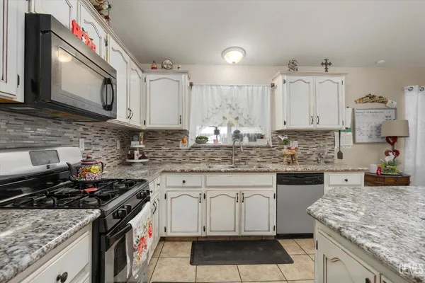 a kitchen with stainless steel appliances granite countertop a stove sink and cabinets