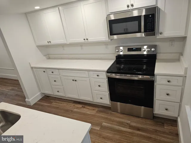 a kitchen with stainless steel appliances white cabinets and a stove a oven with white countertops