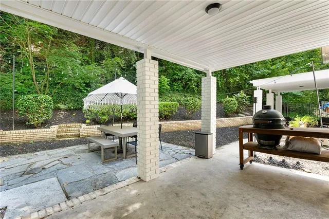 a view of a patio with table and chairs under an umbrella with a big yard
