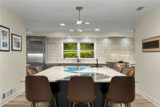 a kitchen with stainless steel appliances granite countertop a sink chairs and a refrigerator