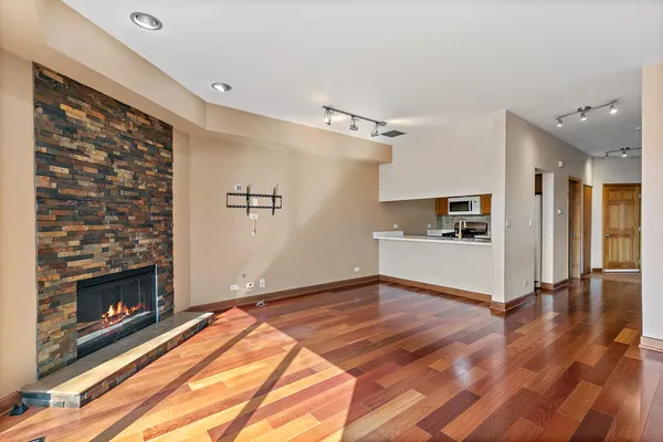 a view of a livingroom with wooden floor and a kitchen