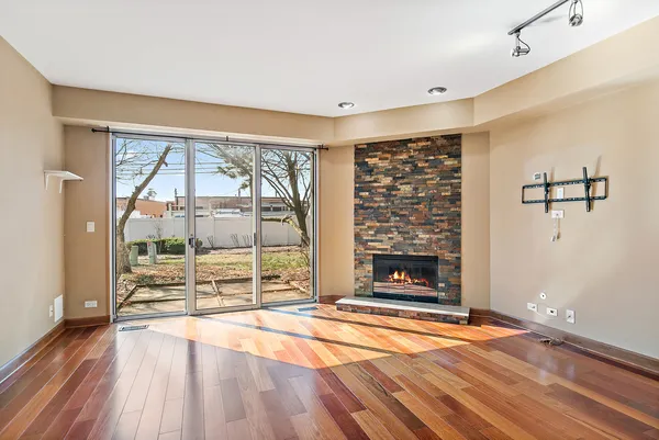 a view of an empty room with wooden floor and a fireplace