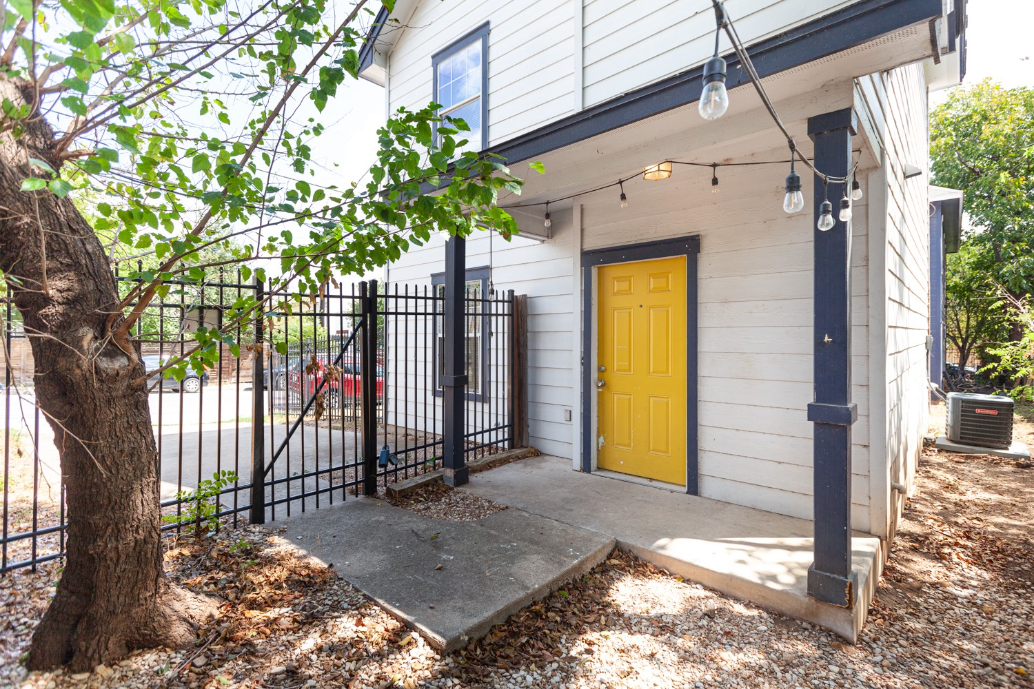2326 Webberville Road, Unit B Austin, TX 78702 - Photo 2 of 15 Entryway featuring a bright yellow door, concrete porch, and string lighting