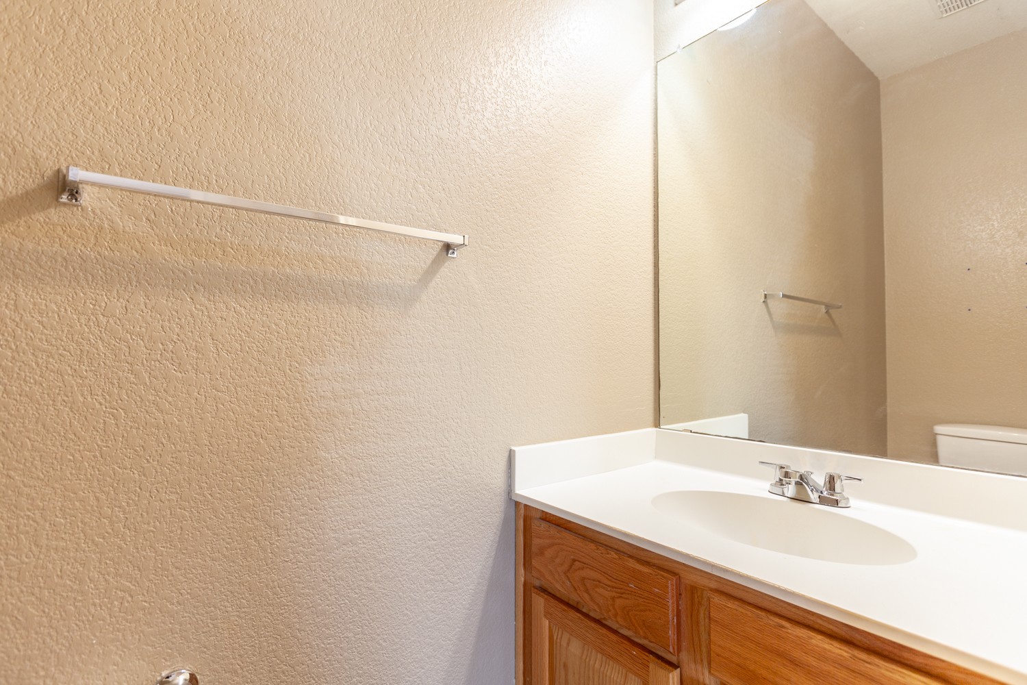 2326 Webberville Road, Unit B Austin, TX 78702 - Photo 9 of 15 Bathroom vanity featuring wood-finish cabinetry, a white countertop with integrated sink, and a chrome faucet