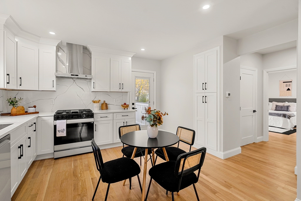 7 Davis Street Saugus, MA 01906 - Photo 13 of 42 a kitchen with stainless steel appliances granite countertop a stove top oven a sink a dining table and chairs with wooden floor