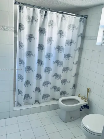 a white toilet sitting next to a shower curtain