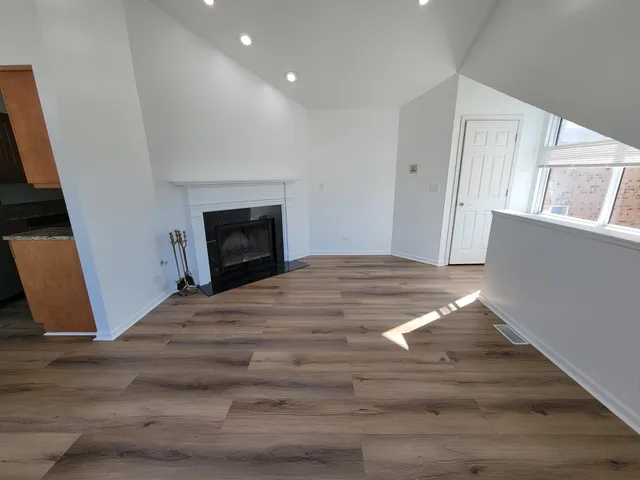 a view of empty room with wooden floor and fireplace