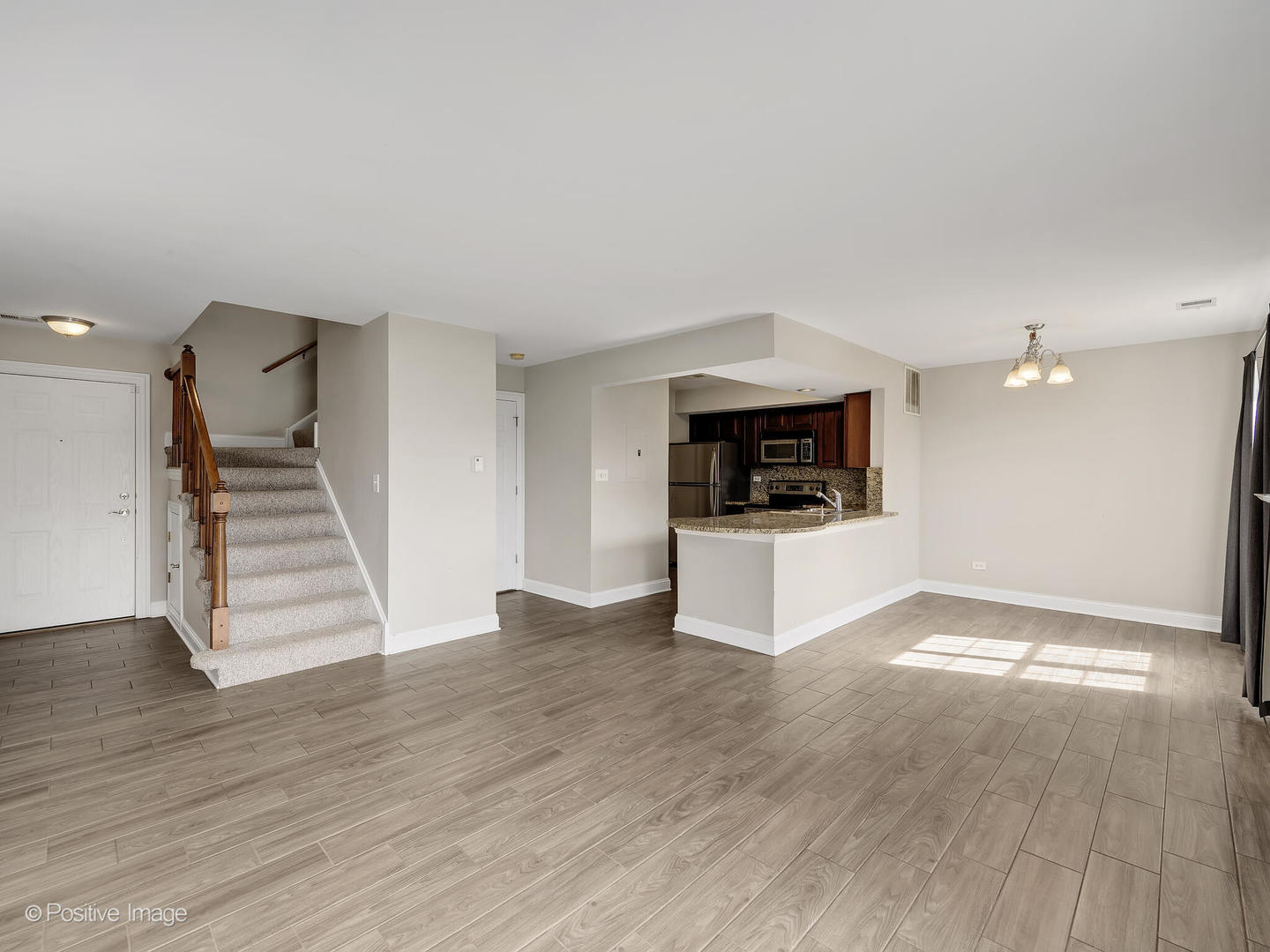 11 Foxcroft Road, Unit 115 Naperville, IL 60565 - Photo 4 of 17 a view of a kitchen and an empty room with wooden floor