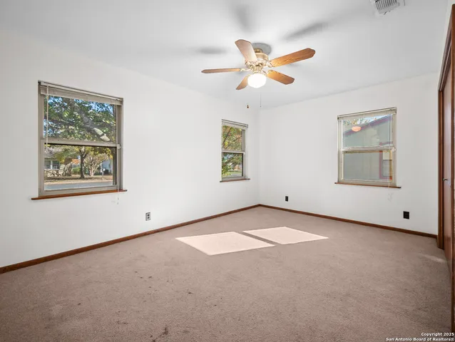 an empty room with windows and fan