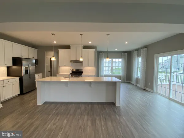 a large kitchen with stainless steel appliances a large counter top a stove and a refrigerator