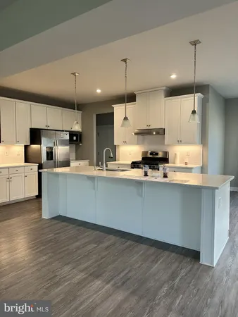 a large kitchen with stainless steel appliances a large counter top a sink a refrigerator and a window