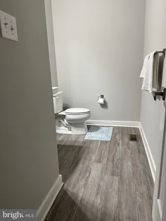 a bathroom with a toilet and a wooden floor