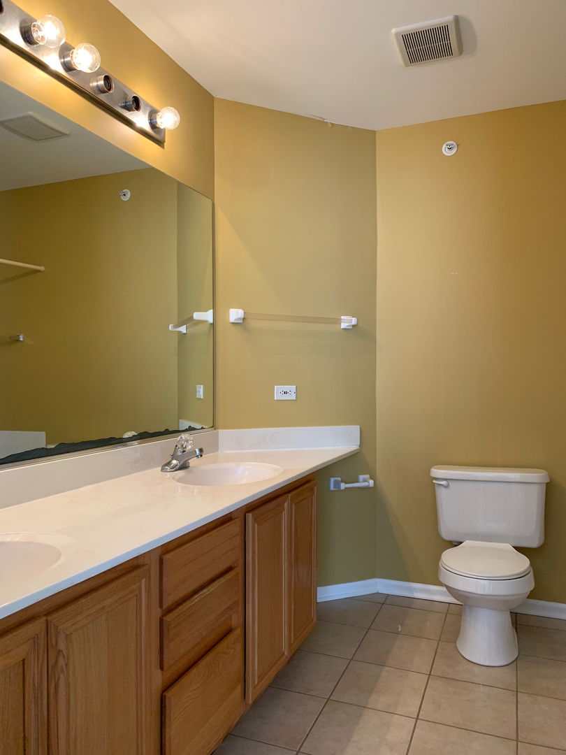 703 Riding Lane, Unit 703 St. Charles, IL 60174 - Photo 16 of 22 a bathroom with a granite countertop sink a toilet and a mirror