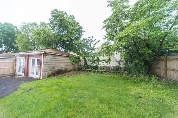 a backyard of a house with lots of plants and large tree