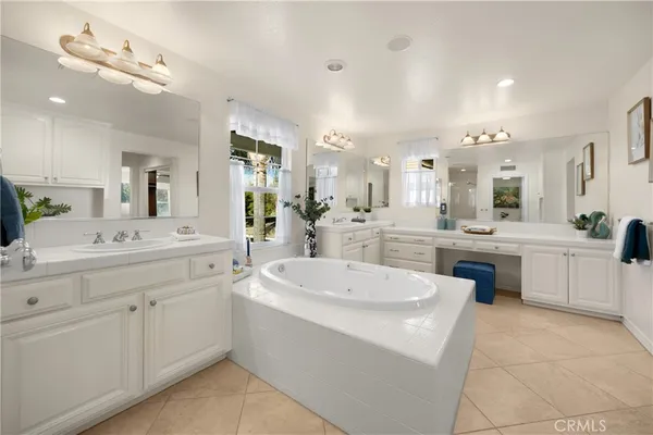 a large white bathroom with a sink a toilet a mirror and vanity