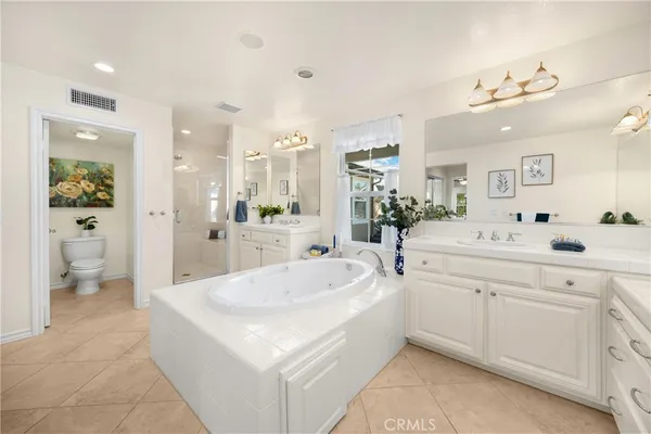 a large white bathroom with a double vanity sink a mirror and a bathtub